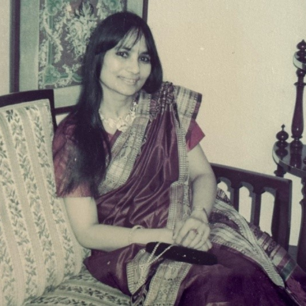 Photo of a young Indian lady in her sari sitting on a sofa smiling